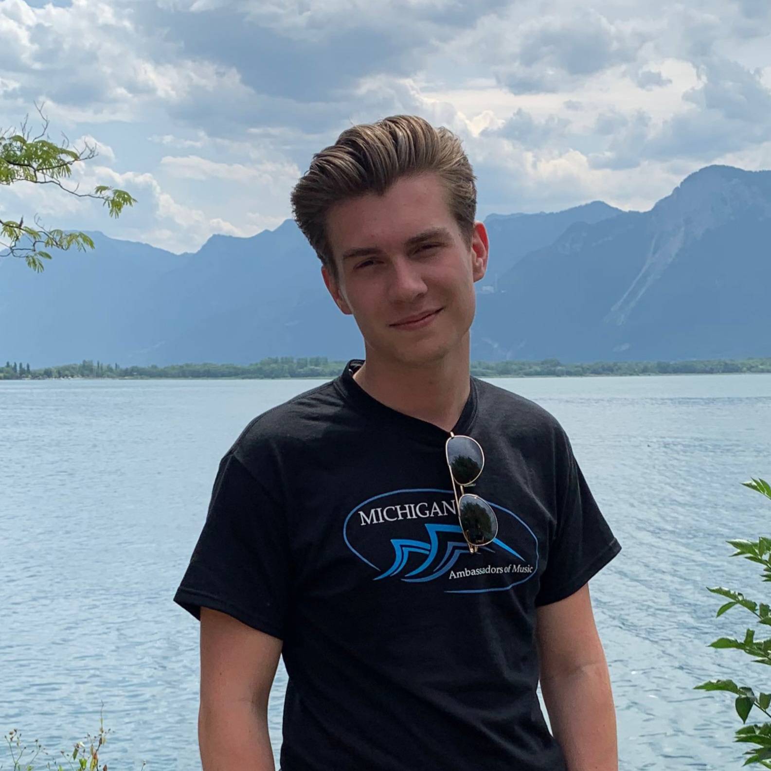 Man in dark blue shirt with lake and mountains in the background